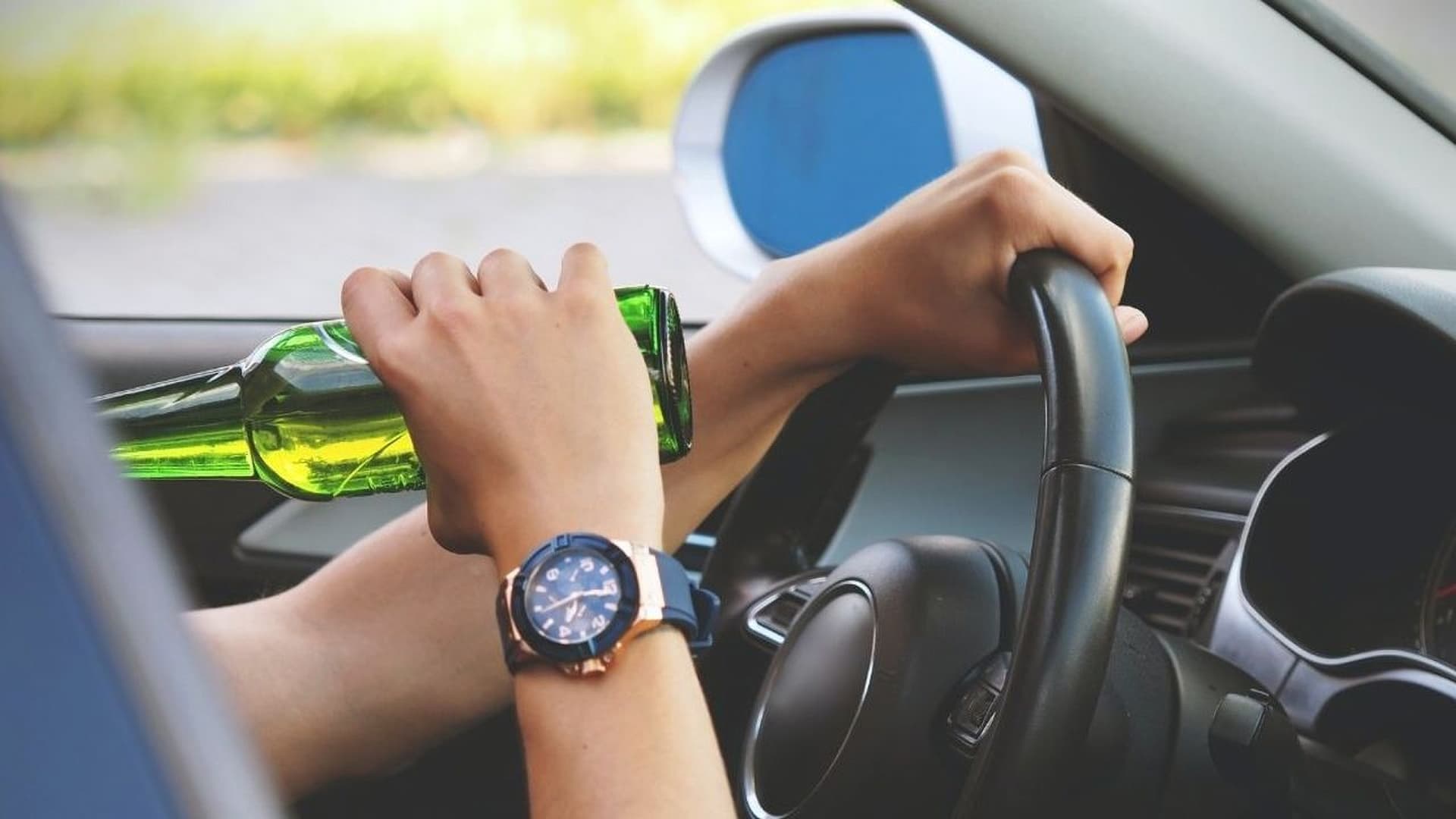 Řidič s flaškou alkoholu za volantem | Zdroj: Sweden Car Hire